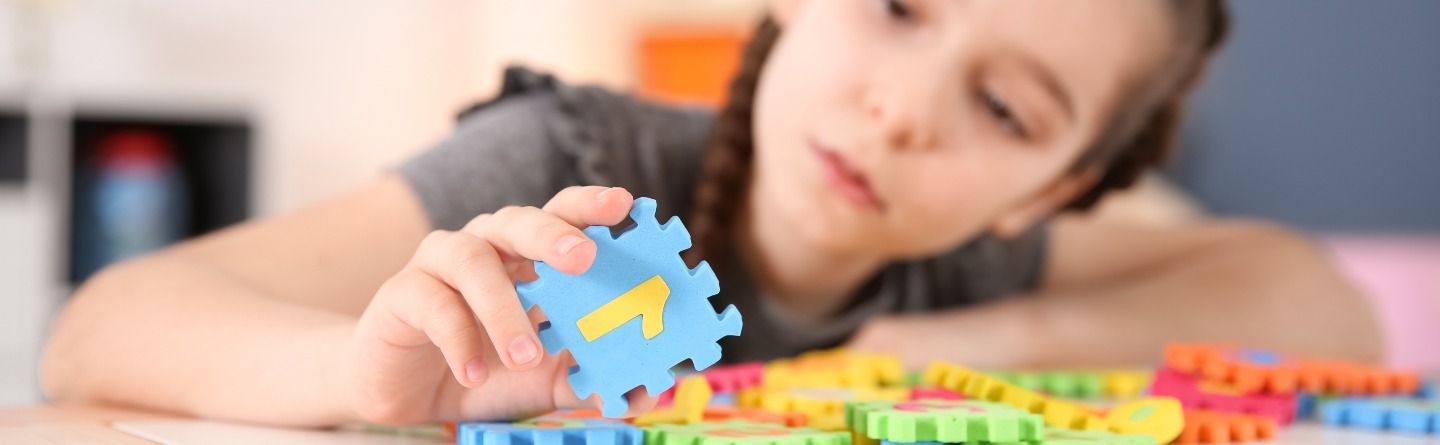 Autismuszentrum Rostock Symbolbild Autismus: Ein Mädchen hält ein buntes Puzzleteil in der Hand.